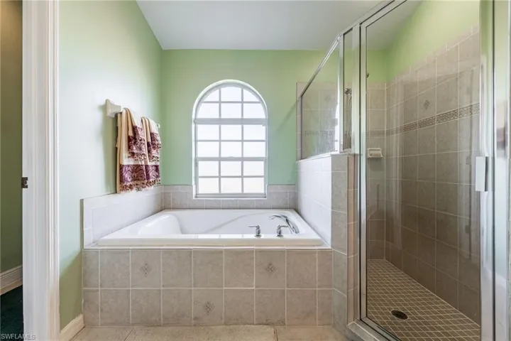 Full bath featuring a stall shower, a garden tub, and tile patterned flooring