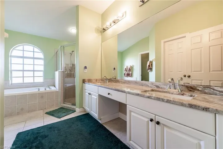 Full bathroom featuring double vanity, a stall shower, light tile patterned flooring, and a bath