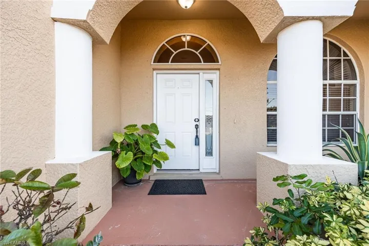 View of exterior entry with stucco siding and covered porch
