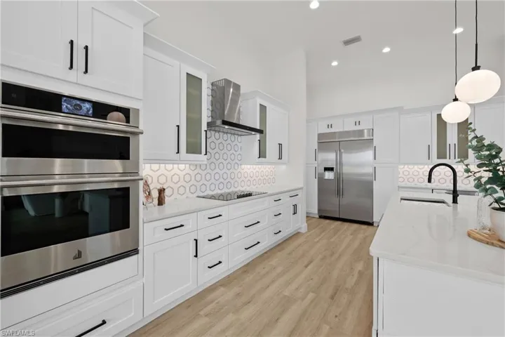 Kitchen featuring appliances with stainless steel finishes, sink, wall chimney range hood, and decorative backsplash