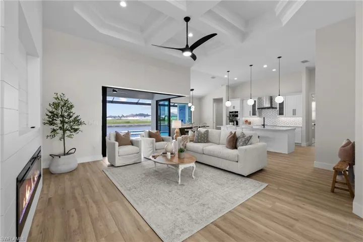 Living room with coffered ceiling, a large fireplace and ceiling fan