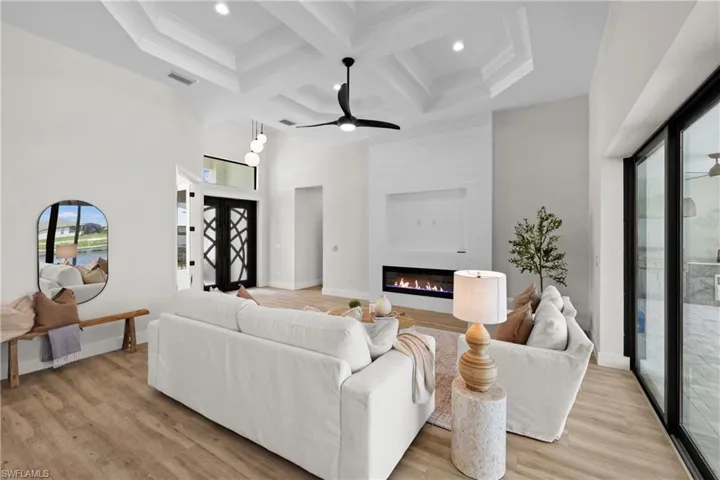 Living room with coffered ceiling, a large fireplace, ceiling fan