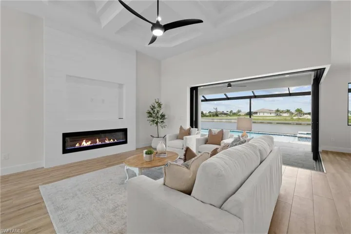 Living room with coffered ceiling, a large fireplace, ceiling fan,