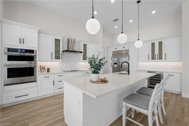 Kitchen featuring stainless steel appliances, decorative backsplash, and a center island with sink
