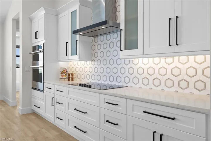 Kitchen tasteful backsplash, white cabinetry, black electric cooktop, and wall chimney range hood