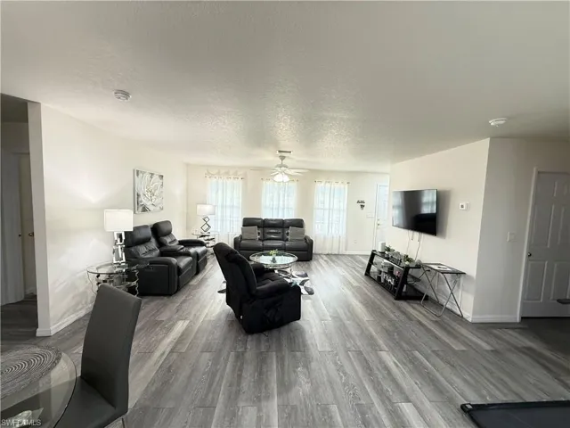 Living area featuring a textured ceiling, wood finished floors, and a ceiling fan