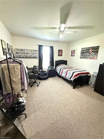 Carpeted bedroom featuring a ceiling fan