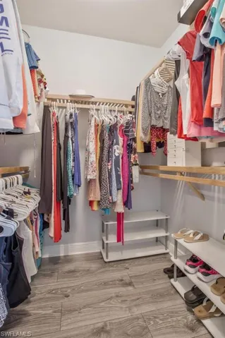 Walk in closet with hardwood / wood-style flooring