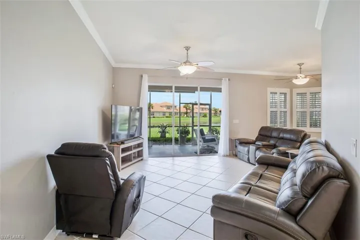 Living room featuring light tile patterned floors, crown molding, and ceiling fan