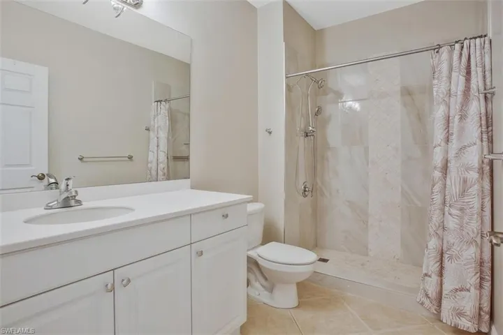 Bathroom featuring a shower with shower curtain, vanity, toilet, and tile patterned flooring