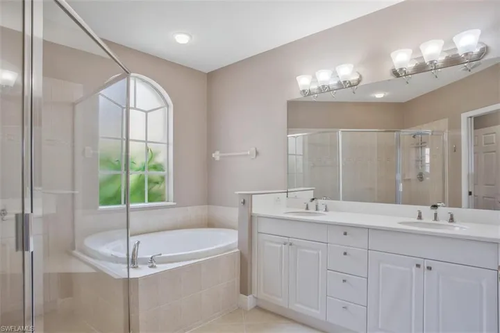 Bathroom with double sink vanity, tile patterned flooring, and separate shower and tub
