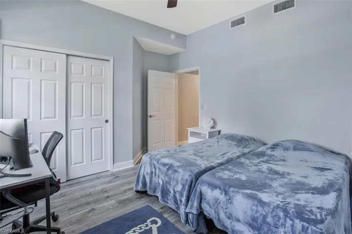 Bedroom with ceiling fan, wood-type flooring, and a closet