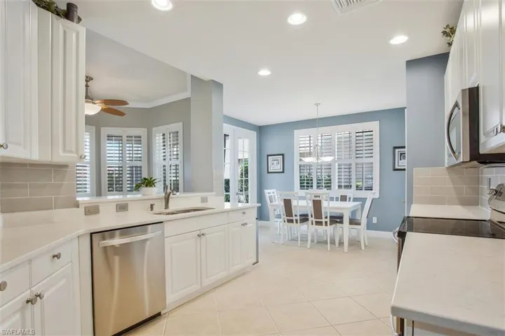 Kitchen featuring appliances with stainless steel finishes, hanging light fixtures, sink, white cabinets, and decorative backsplash