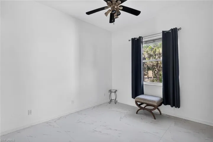 Spare room with marble look tile flooring and a ceiling fan