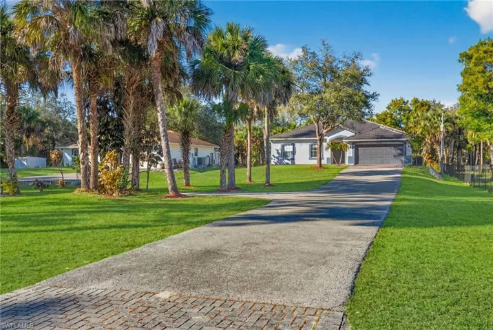 View of front of property with driveway, a front yard, and a garage