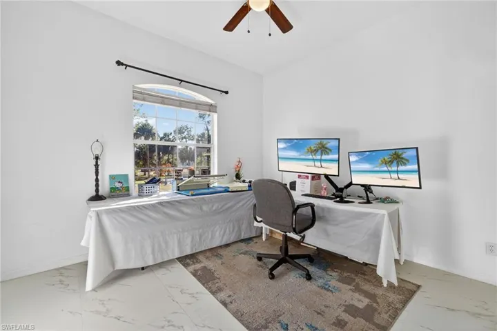 Bedroom with an office area, ceiling fan, light marble finish floors, and lofted ceiling