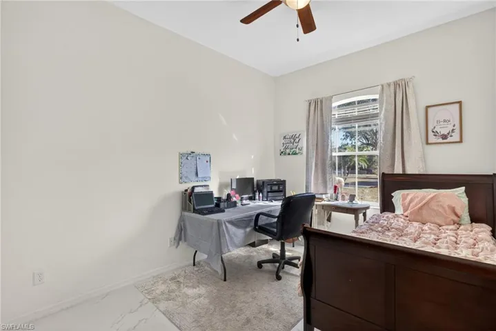 Bedroom featuring a desk, marble finish floors, and ceiling fan