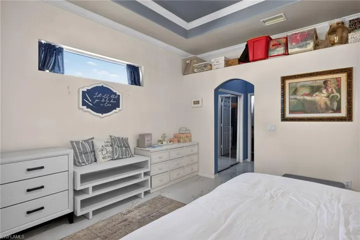 Bedroom featuring arched walkways, ornamental molding, and light marble finish floors