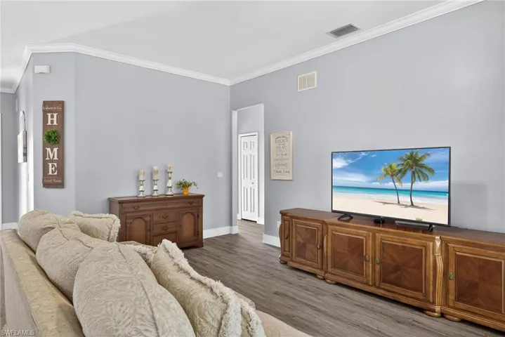 Living area with ornamental molding and wood finished floors