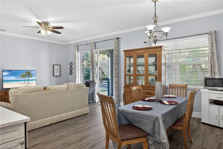 Dining room with ornamental molding, hanging lights, dark wood finished floors, and ceiling fan