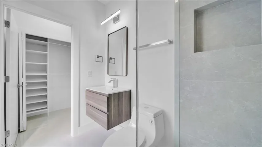 Full bathroom with vanity, a spacious closet, and a shower