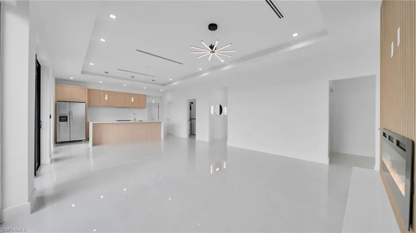 Unfurnished living room with a tray ceiling, recessed lighting, and a chandelier