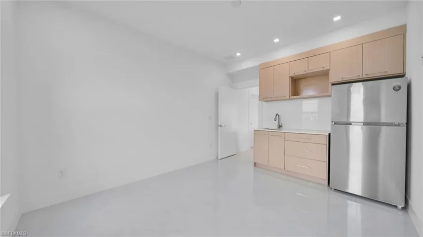 Kitchen featuring light brown cabinetry, freestanding refrigerator, light countertops, modern cabinets, and recessed lighting