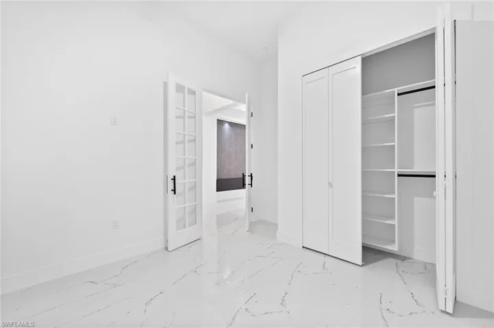 Unfurnished bedroom with a closet, light marble finish flooring, and french doors