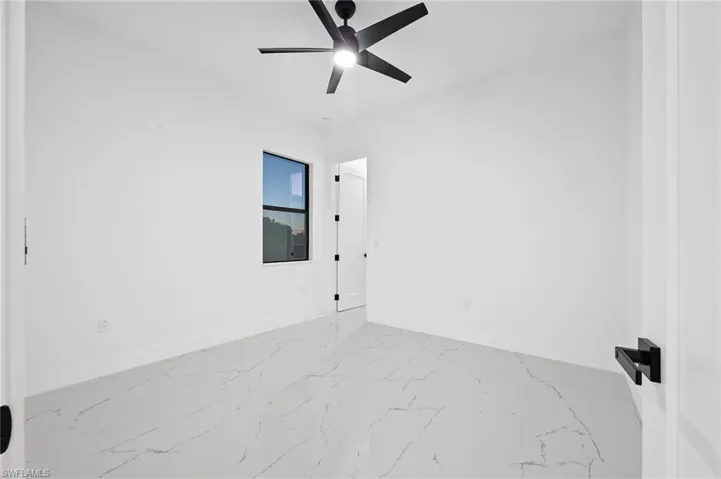 Unfurnished room with light marble finish floors and a ceiling fan