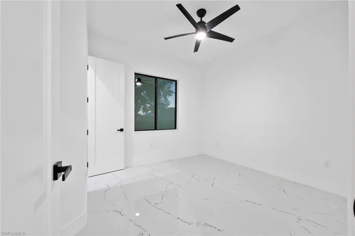 Spare room featuring light marble finish floors and a ceiling fan