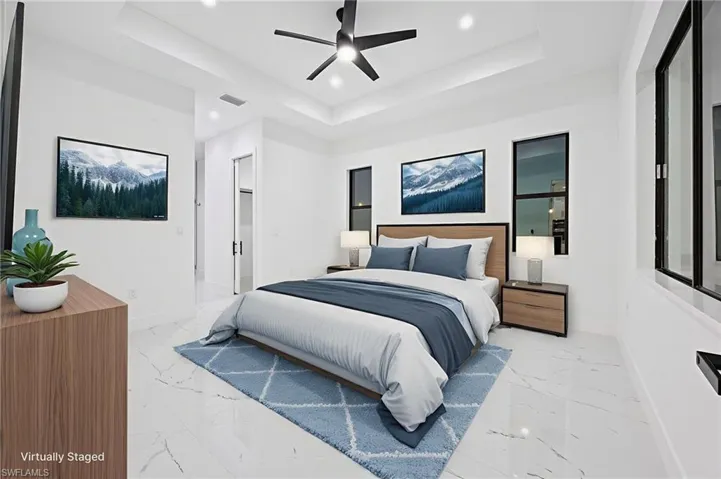 Bedroom featuring a raised ceiling, light marble finish floors, ceiling fan, and recessed lighting