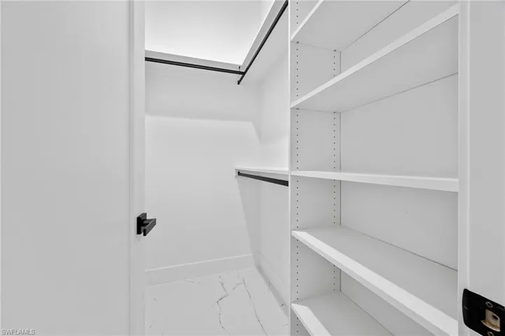 Spacious closet featuring light marble finish flooring