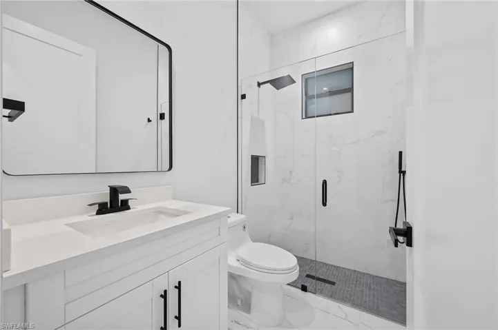 Bathroom featuring vanity, light marble finish flooring, and a marble finish shower
