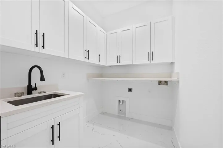 Laundry area featuring electric dryer hookup, light marble finish floors, cabinet space, and washer hookup