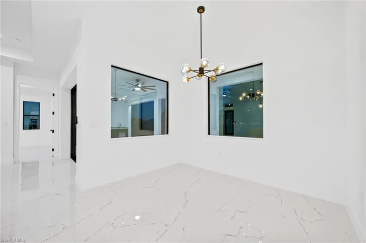 Spare room with a chandelier, a ceiling fan, and light marble finish flooring