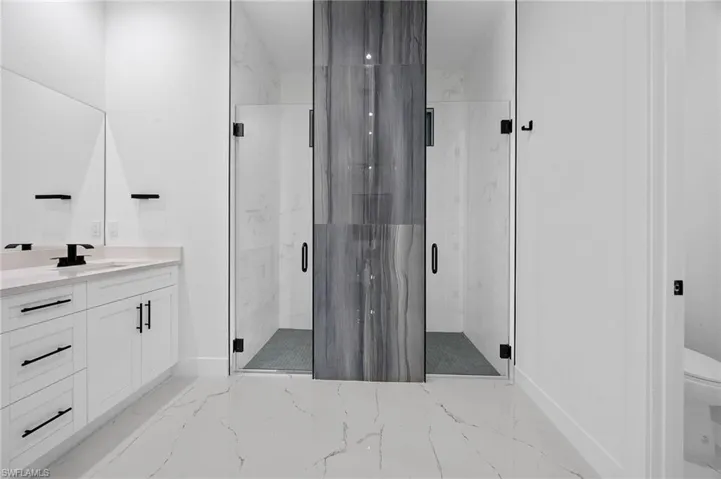 Full bathroom featuring light marble finish flooring, a marble finish shower, and vanity