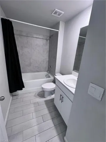 Bathroom featuring vanity and shower / bathtub combination with curtain