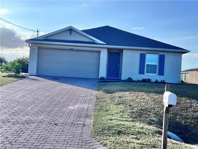 Ranch-style house with decorative driveway, stucco siding, a garage, roof with shingles, and a front yard