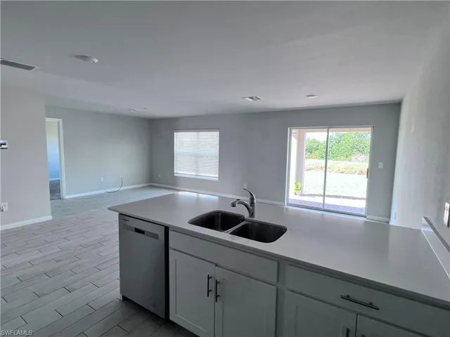 Kitchen with dishwasher, plenty of natural light, open floor plan, and white cabinets