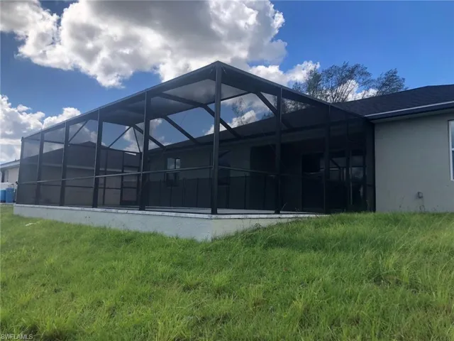 View of property exterior featuring a lawn and glass enclosure