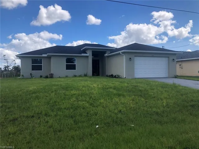 View of front of house with a garage and a front lawn