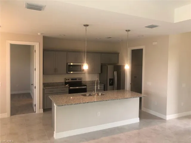 Kitchen featuring pendant lighting, appliances with stainless steel finishes, sink, and a kitchen island with sink
