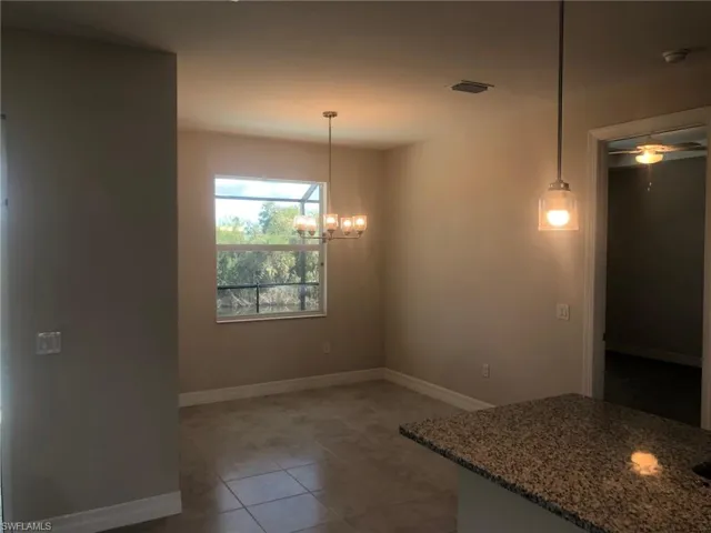 Unfurnished dining area featuring ceiling fan with notable chandelier and tile patterned floors