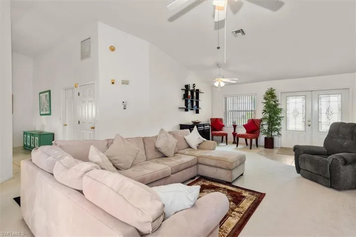 Spacious living area featuring vaulted ceilings, ceiling fans, and neutral wall tones