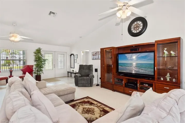 Spacious living area featuring vaulted ceilings, ceiling fans, and a built-in media center with integrated display cases