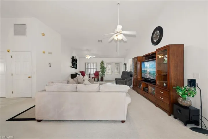 Vaulted ceilings and light-colored carpet enhance the spaciousness of this interior room