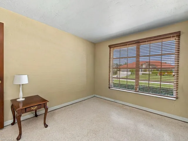 Room featuring neutral wall finishes, stone-composite flooring, and a large window equipped with horizontal wooden blinds