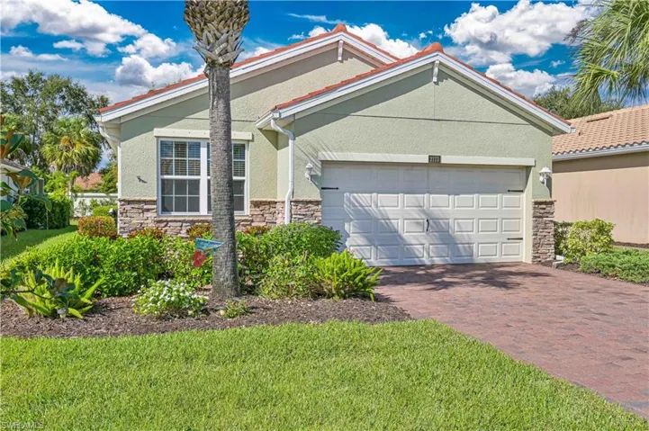 View of front of property with stone siding, decorative driveway, stucco siding, and an attached garage