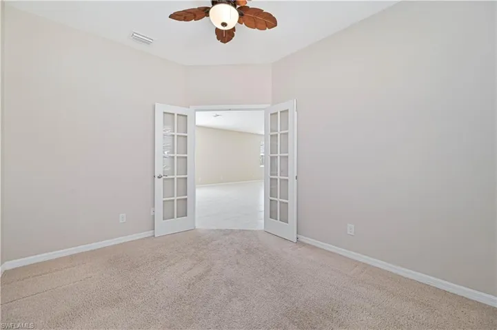 Unfurnished room featuring french doors, light carpet, and a ceiling fan