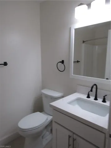 Bathroom featuring a white vanity with an integrated sink, matte black faucet, and a wall-mounted mirror
